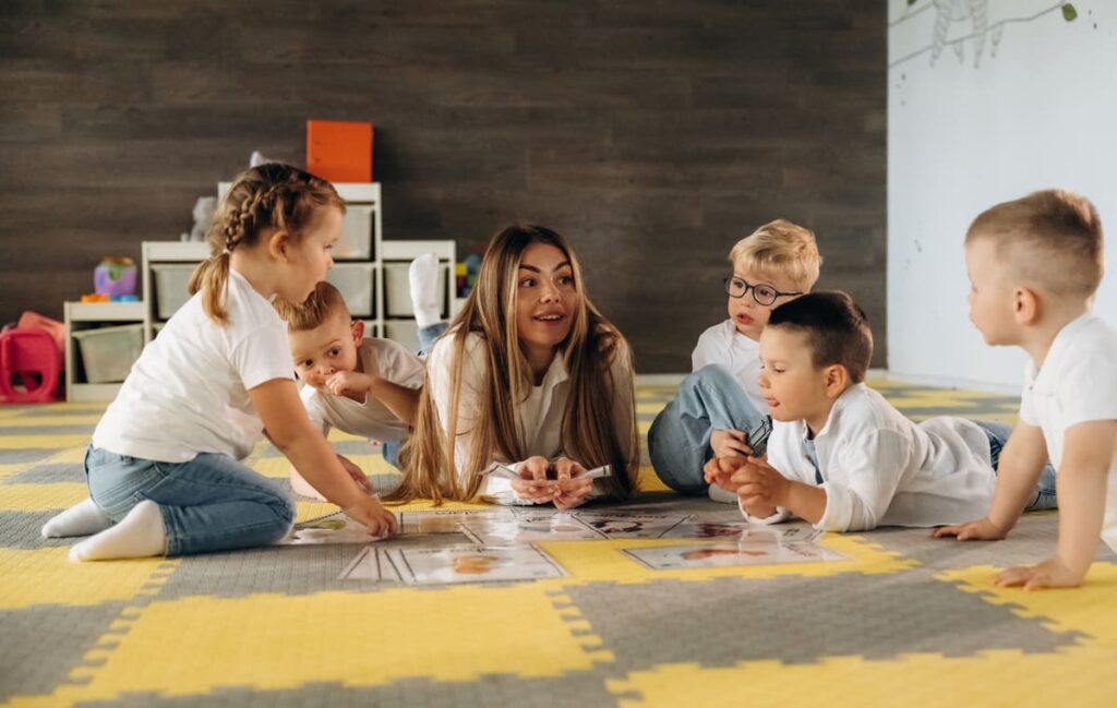 Niños en el aula infantil participando en una actividad de juego dirigido guiada por una maestra.