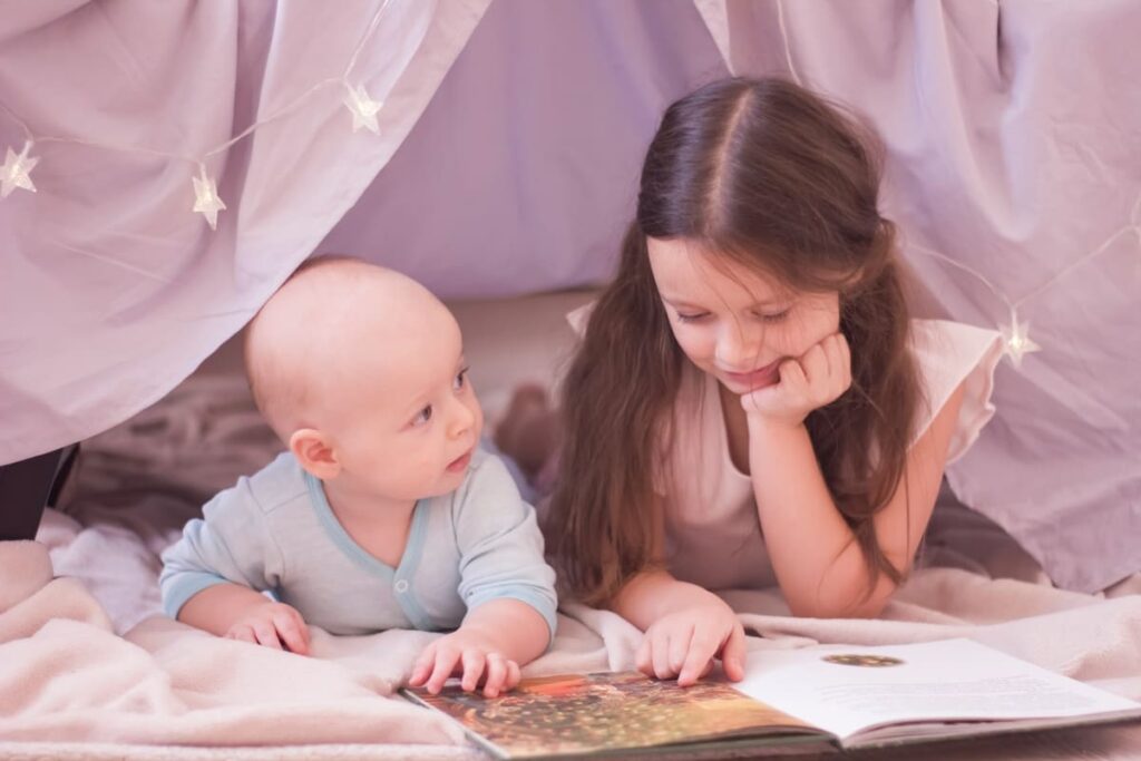 leyendo un cuento a su hermana como técnica para estimular el lenguaje desde casa.